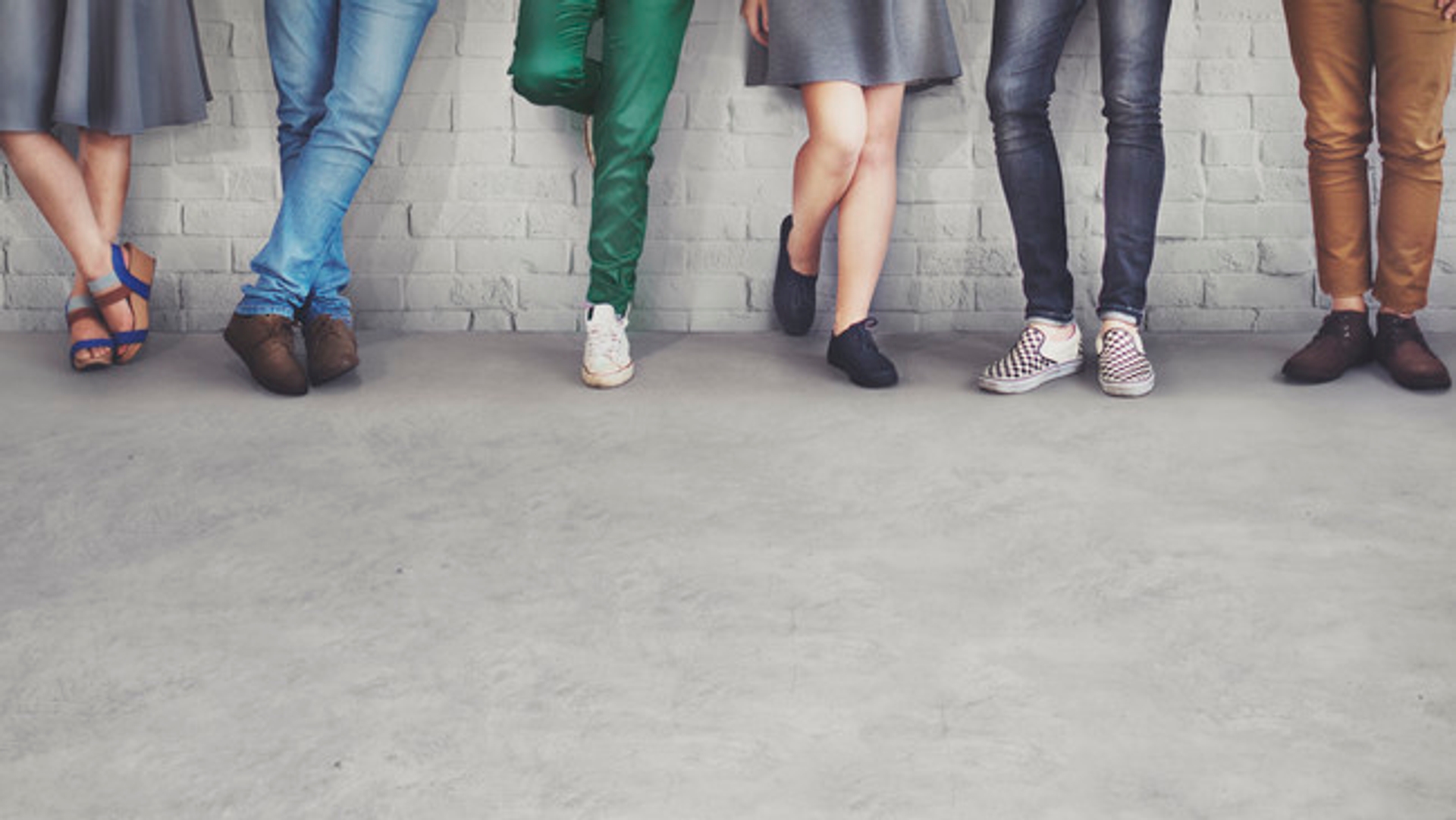 Young people's feet standing against a wall