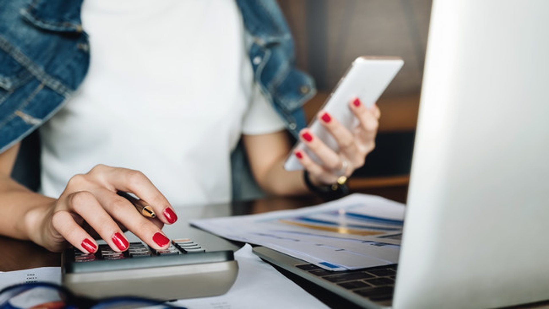 image: person checking a phone while working at desk