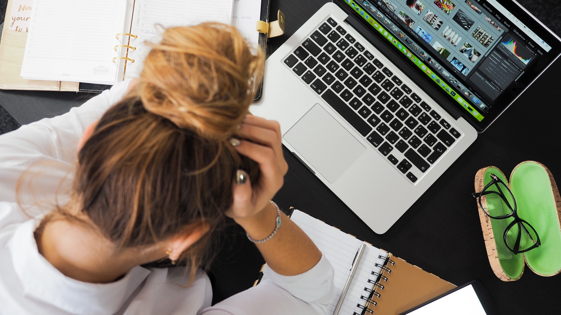 person with head in their hands in front of laptop