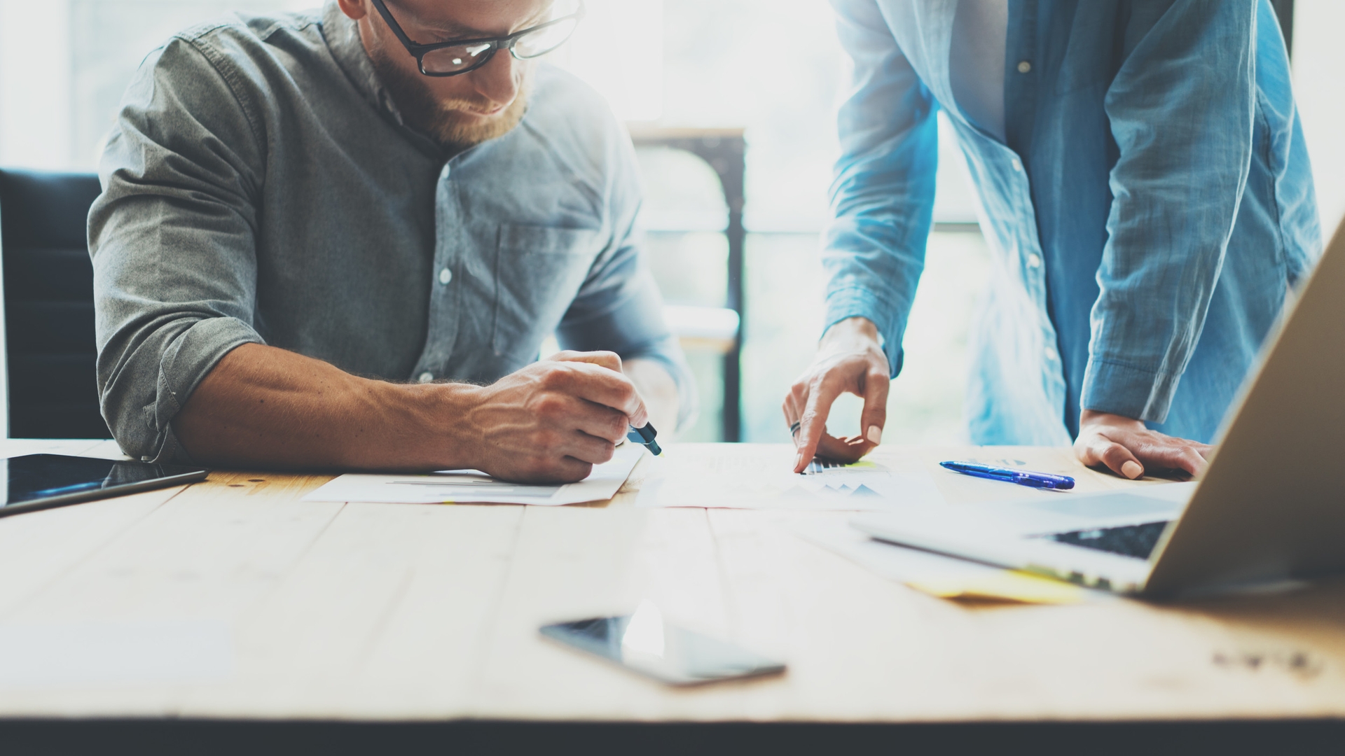 Man with glasses and beard being mentored at desk