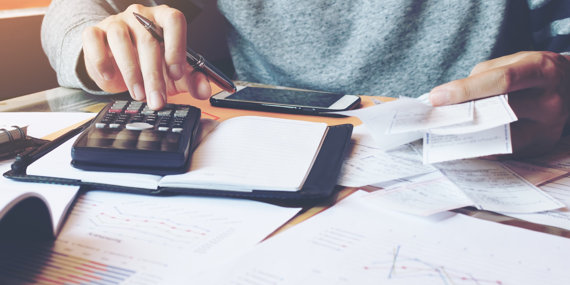 person typing at a calculator on a desk