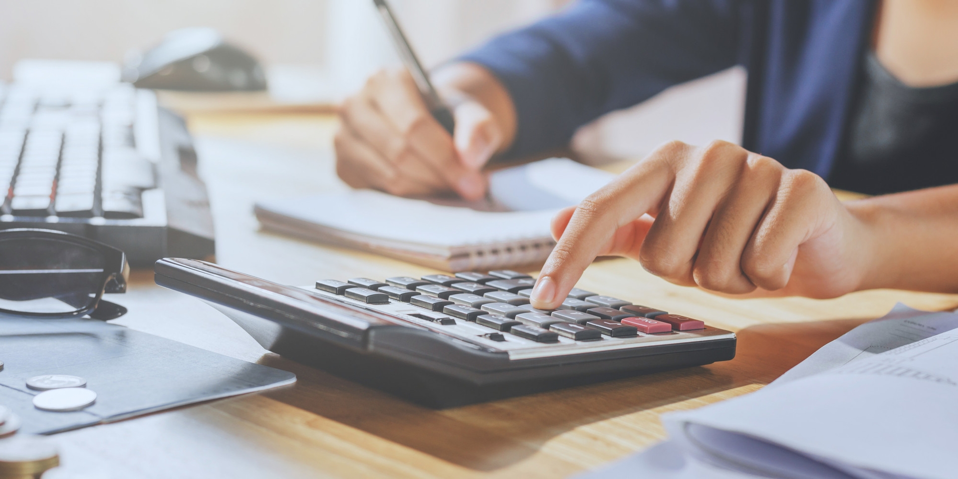 Person working on a desk with a calculator and paperwork