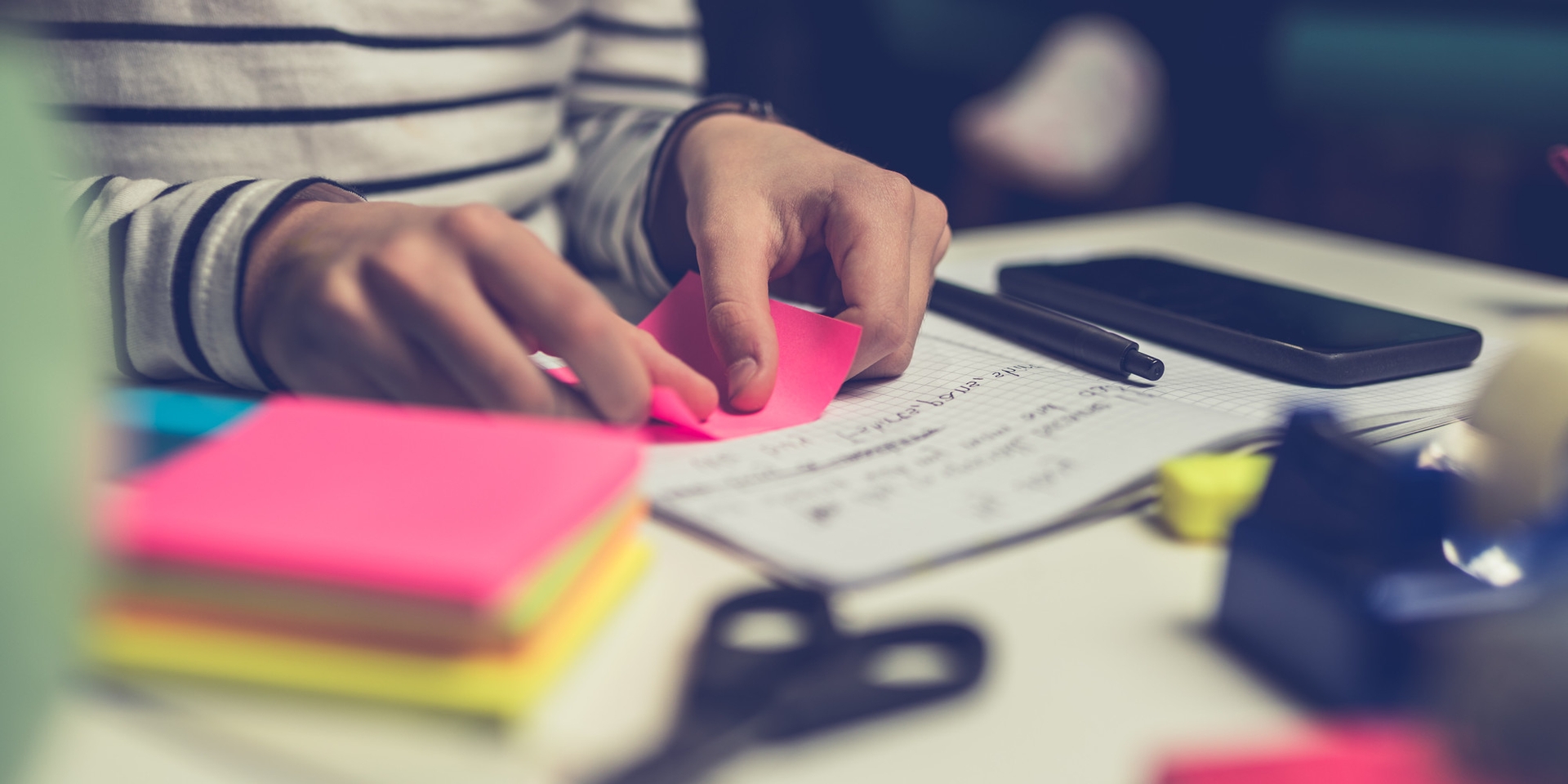 A person studying at a desk and sticking post-it notes into study books.